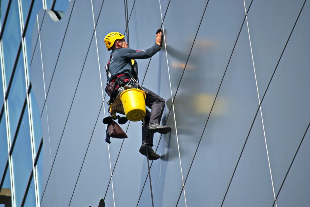 persona trabajando en alturas limpiando vidrios de un edificio