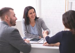 tres personas en una reunión y dos mujeres estrechando la mano