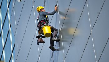 persona trabajando en alturas limpiando vidrios de un edificio