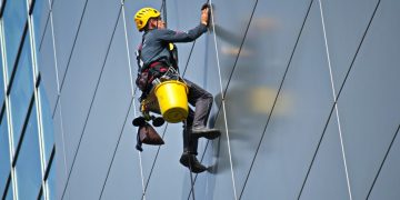 persona trabajando en alturas limpiando vidrios de un edificio