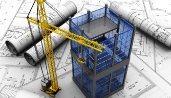 planos sobre un escritorio con una grúa y el modelo de un edificio