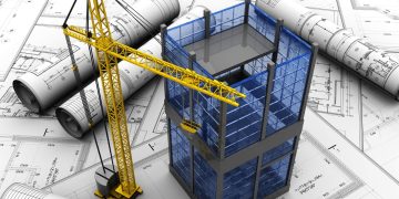 planos sobre un escritorio con una grúa y el modelo de un edificio