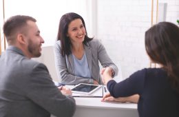 tres personas en una reunión y dos mujeres estrechando la mano