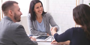 tres personas en una reunión y dos mujeres estrechando la mano